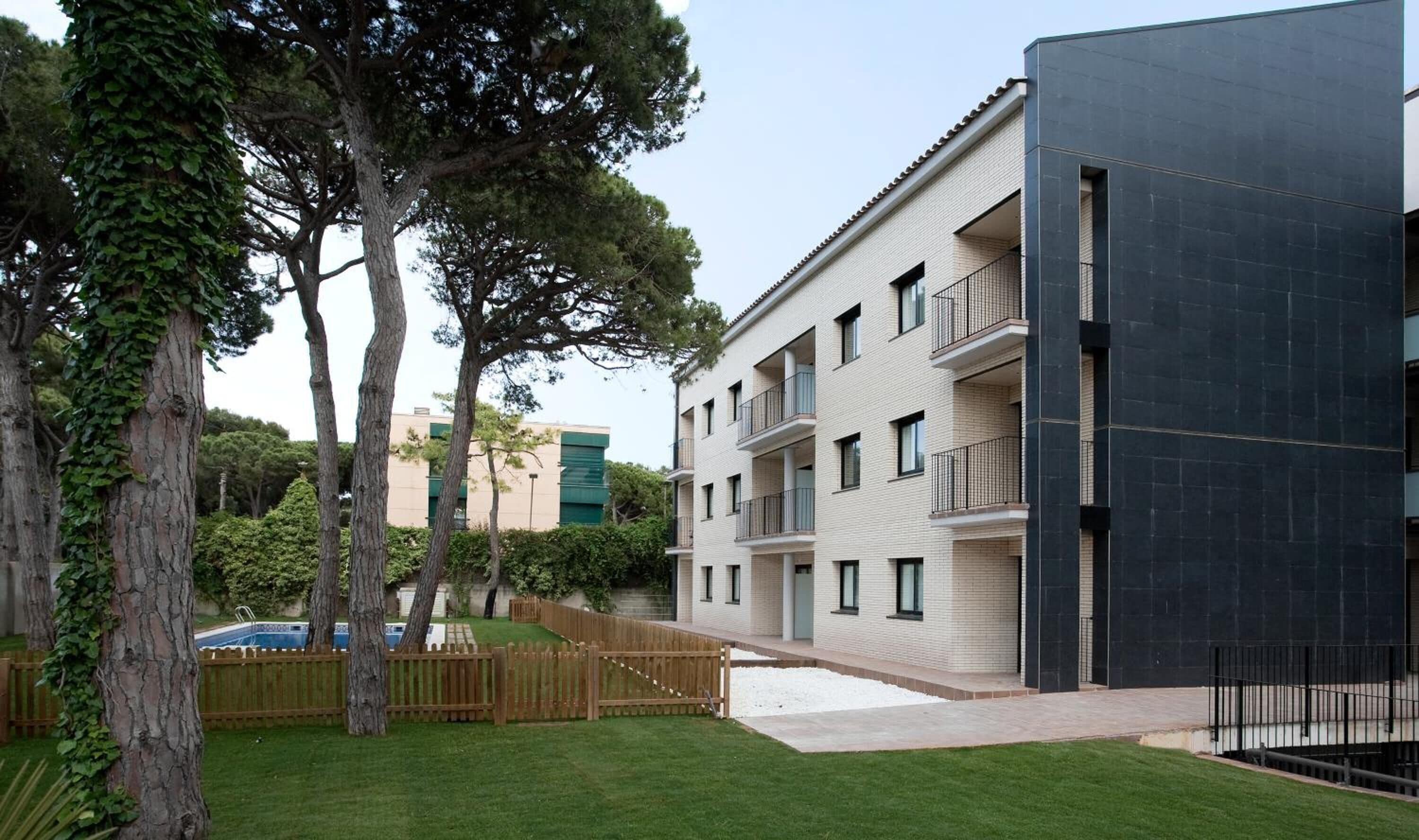 A modern apartment building with multiple balconies, a swimming pool, and a well-maintained garden.
