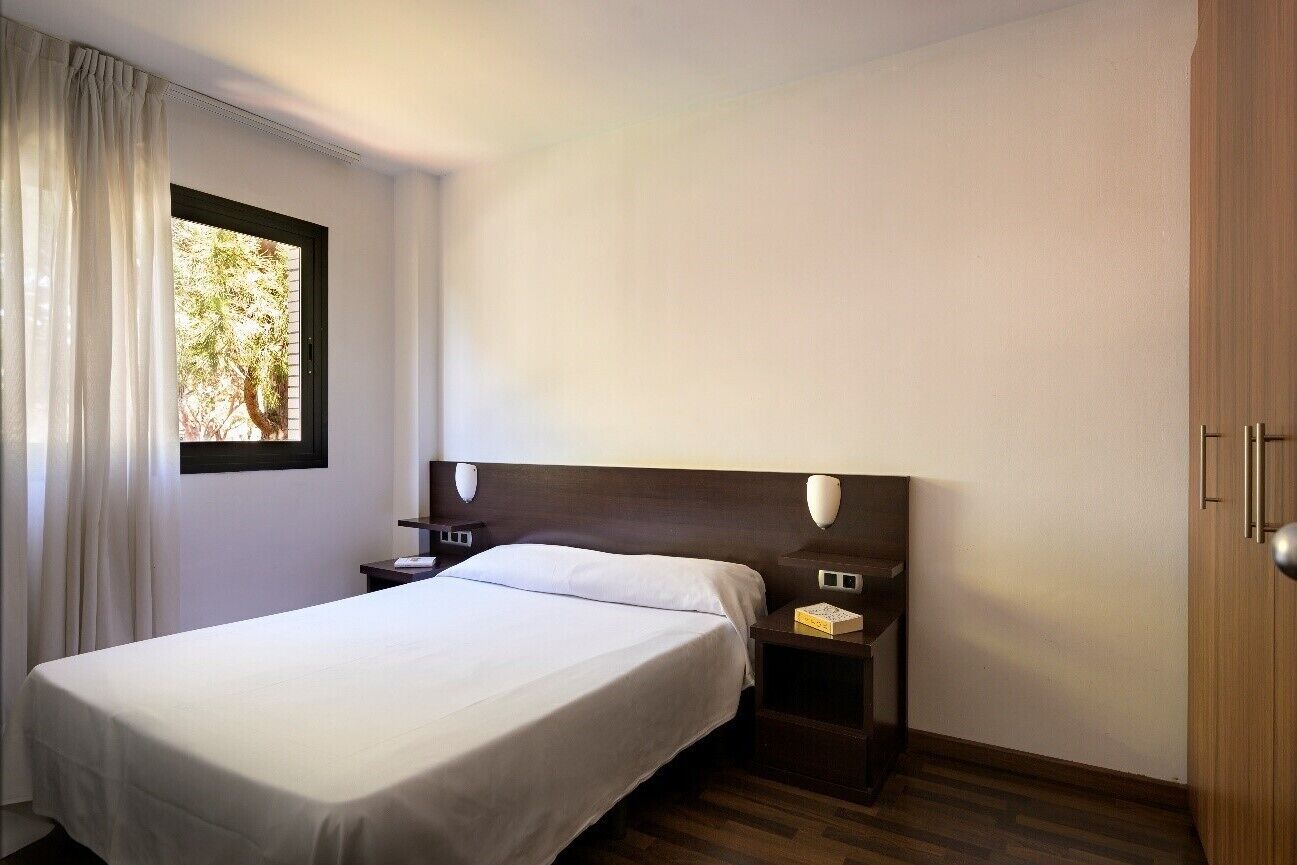 Una habitación de hotel con una cama individual, una mesita de noche y un armario de madera.