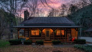 A log cabin with a porch, a chimney, and a small garden area.
