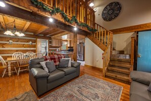 Cozy living area with a leather sofa, dining table, and staircase leading to an upper level.