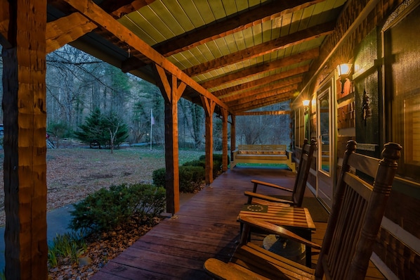 Relax on the covered porch surrounded by trees and a lush lawn.
