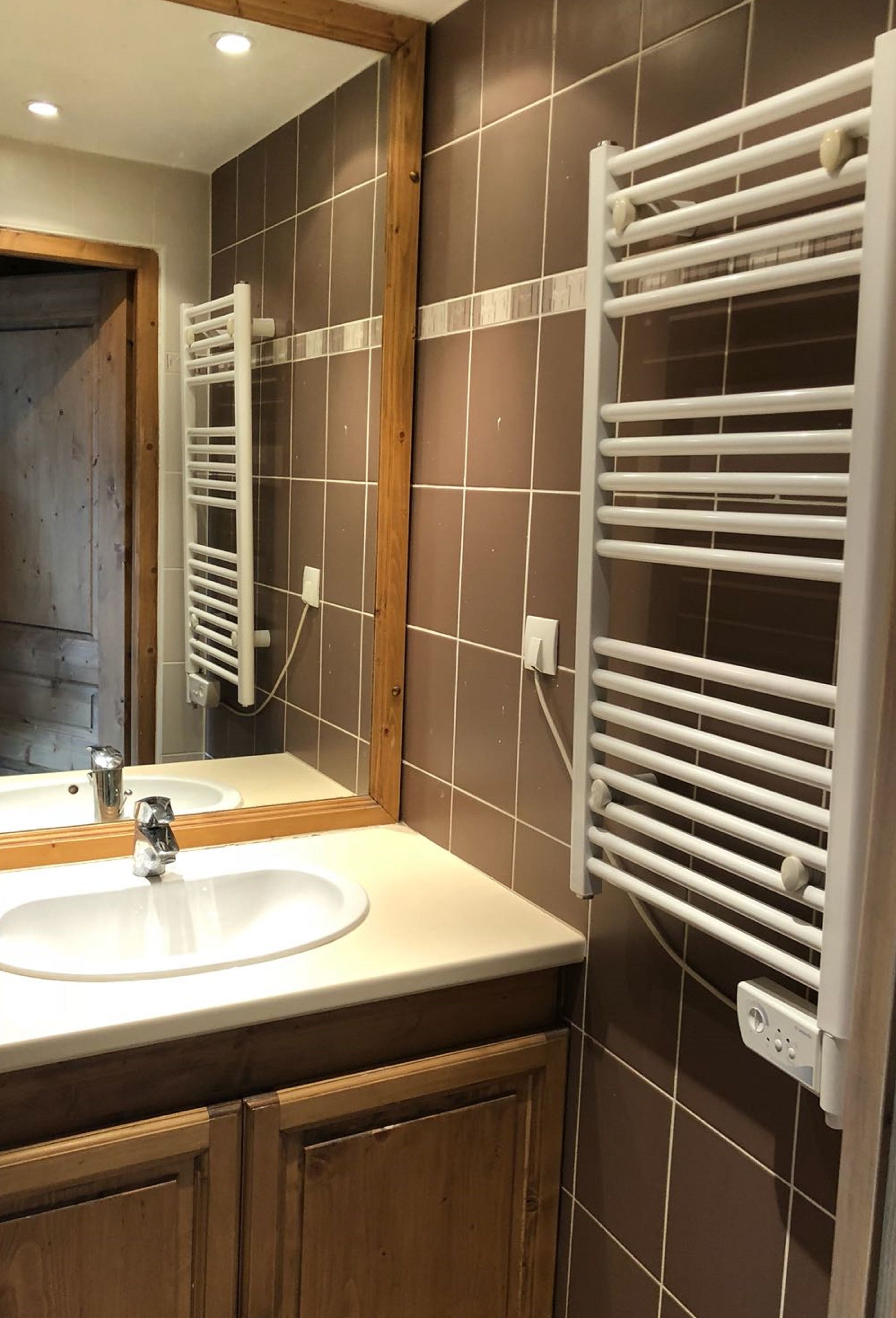 A bathroom with a sink, mirror, and two towel racks.