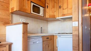 Eine kleine Küche mit Holzschränken, einer Mikrowelle, einem Geschirrspüler und einem Kühlschrank.