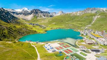 An aerial view of a mountainous area with a large turquoise lake, a ski resort, and a small town with buildings and roads.