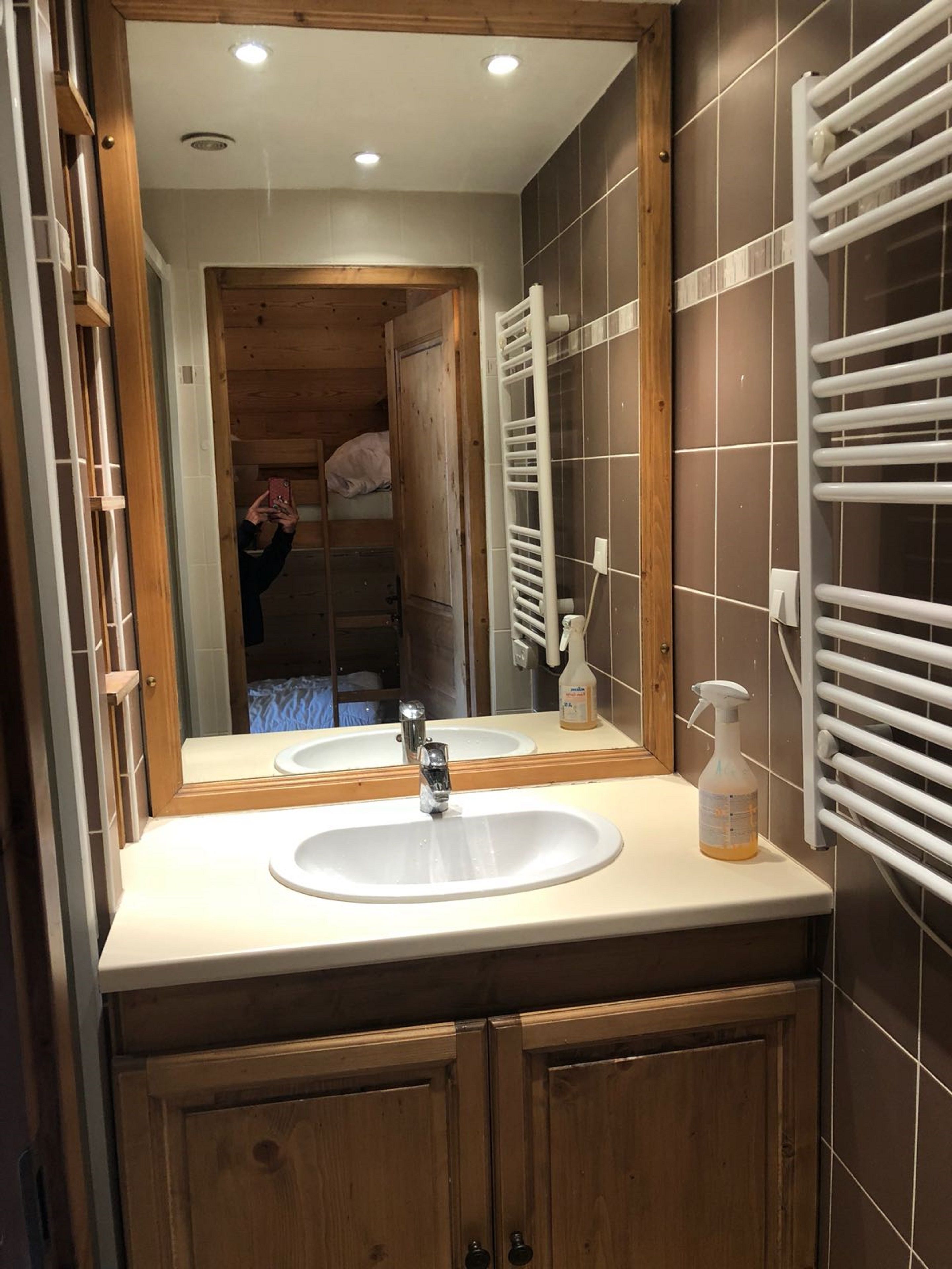 Un baño con tocador de madera, un lavabo blanco, un espejo y un perchero para toallas.