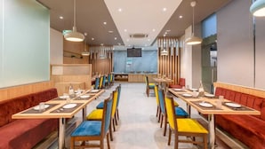 Uma sala de jantar moderna com várias mesas e cabines, equipada com cadeiras e louças postas.