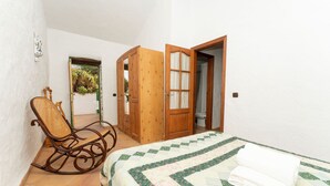 A bedroom with a bed, a rocking chair, and a wooden wardrobe. - Casa Rural La Capellania Tenerife, Casa Verde (Granadilla)