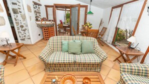 A cozy living room with a checkered sofa, a wooden coffee table with decorative items, and a dining area with a table and chairs. - Casa Rural La Capellania Tenerife, Casa Verde (Granadilla)