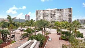 Ein modernes Hotel mit großem Parkplatz, Palmen und blauem Himmel.