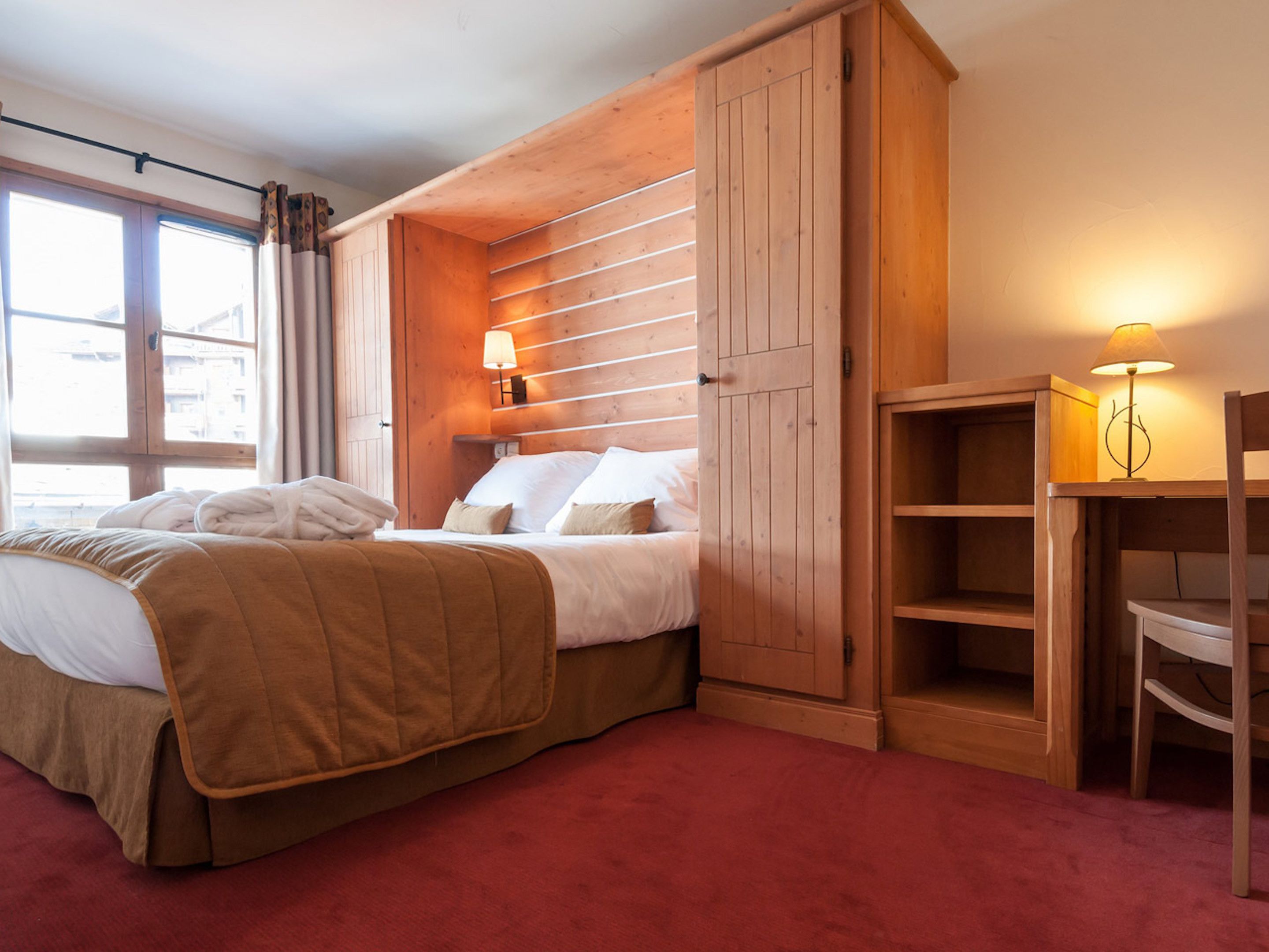 Une chambre à coucher avec un lit, une armoire en bois et une table de chevet avec une lampe.