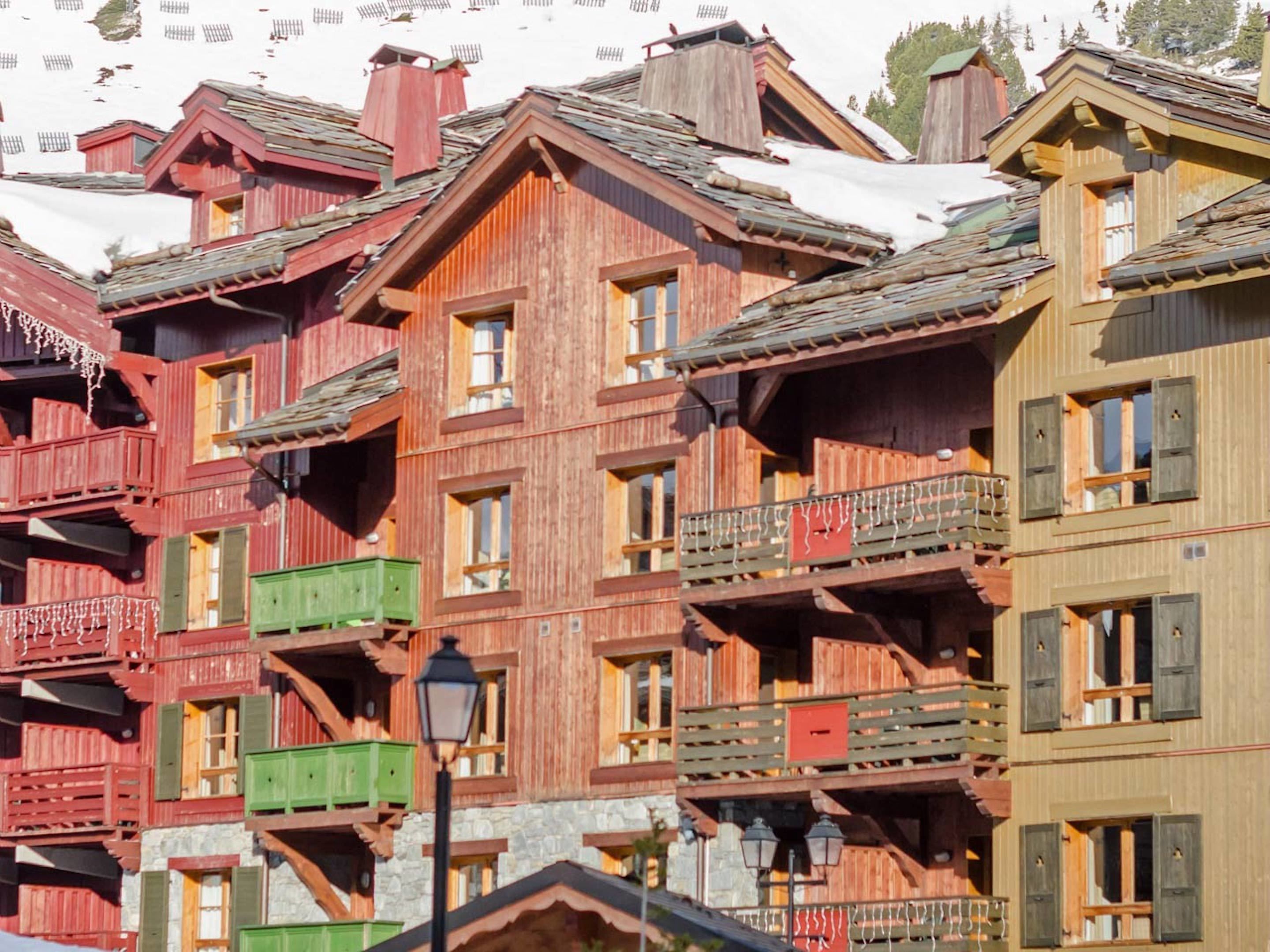 A row of multi-story wooden buildings with balconies and steeply pitched roofs, likely part of a mountain resort.