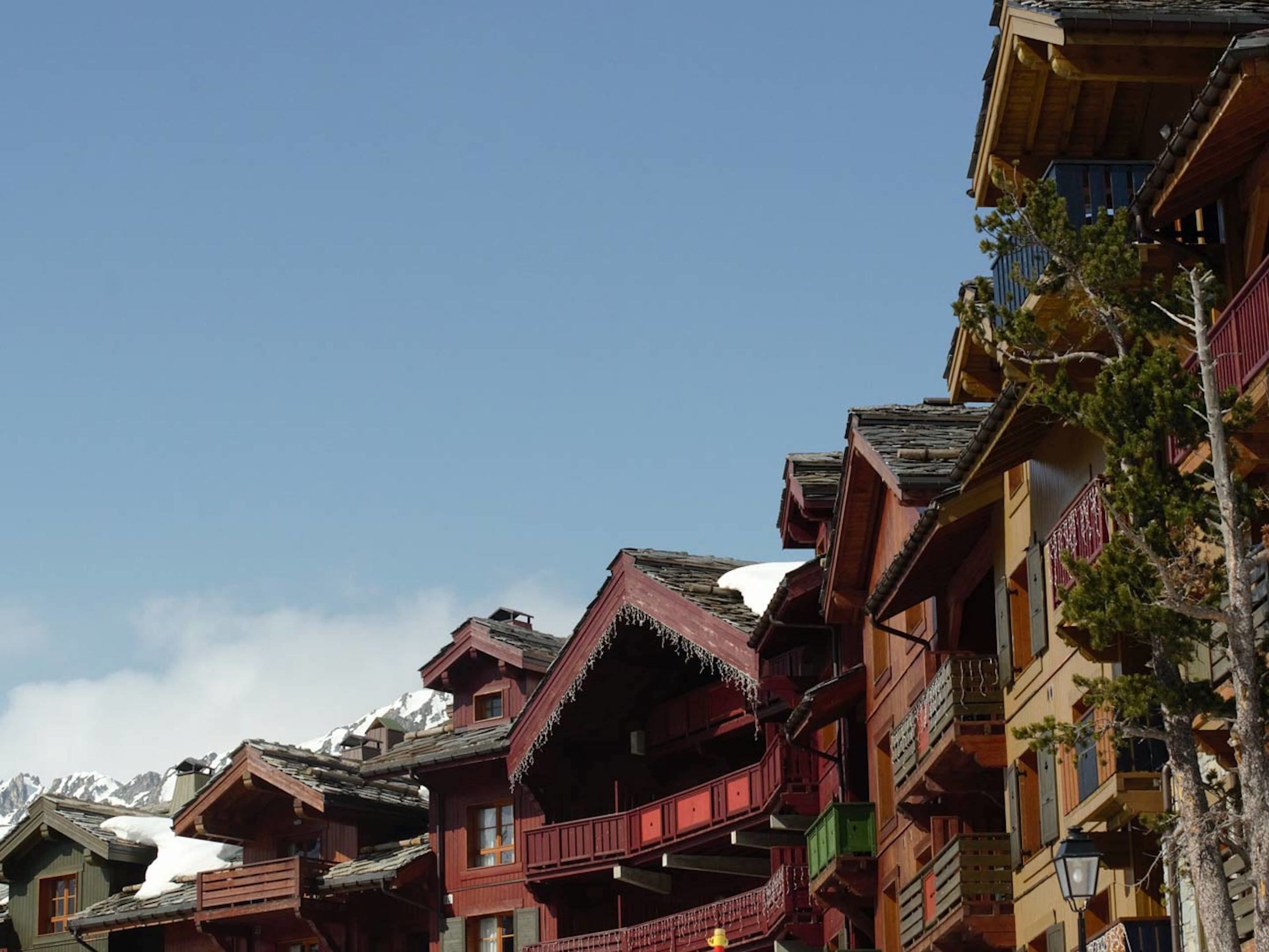 Un chalet traditionnel en bois, doté de nombreux balcons, de toits à forte pente et surplombant un paysage montagneux.