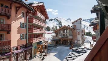 A traditional alpine village with wooden buildings, balconies, and a snow-covered mountain backdrop.