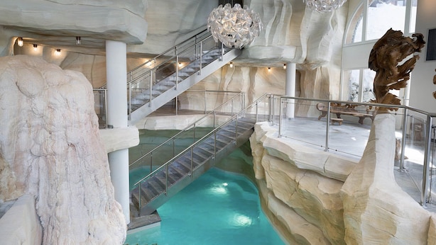 Ein mehrstöckiger Pool im Innenbereich mit Glasgeländern und einer zentralen Treppe.