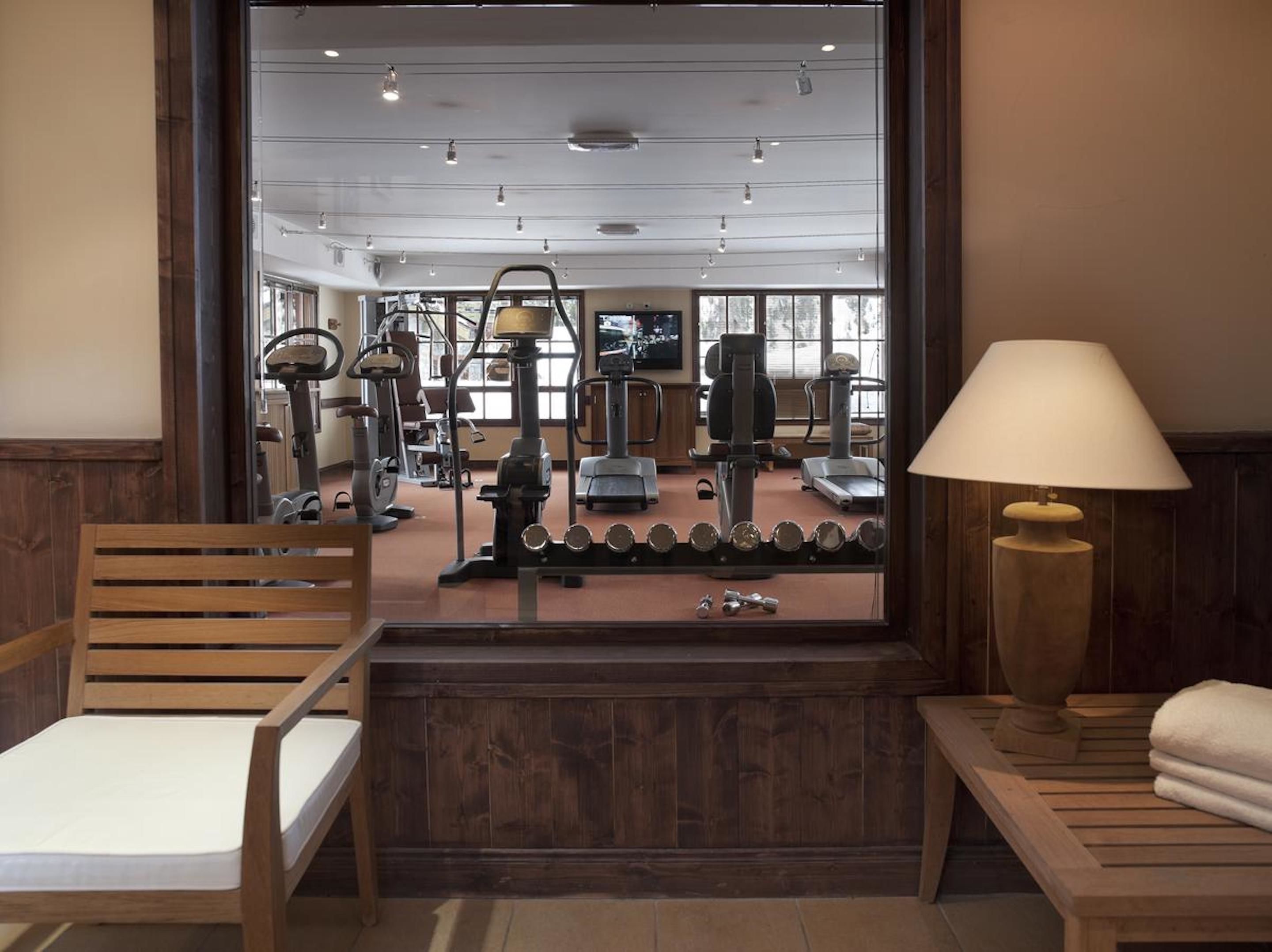 A gym with exercise equipment, a wooden bench, and a lamp.