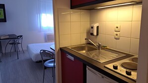 Een kleine keuken met een spoelbak, een kookplaat en een zeepdispenser.