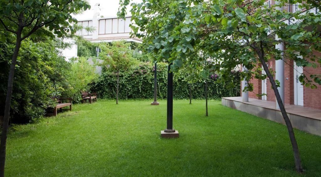 Een verzorgde binnenplaats met gazon, enkele bomen en banken.