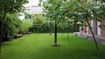 A well-maintained courtyard with a grassy lawn, several trees, and benches.