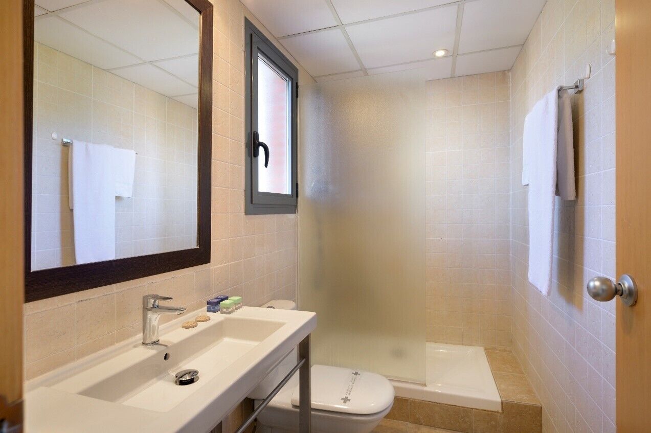 A bathroom with a sink, mirror, toilet, and shower.