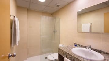 A bathroom with a glass-enclosed shower, a sink with a granite countertop, and a toilet.