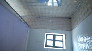A room with a tiled ceiling, a small window, and visible plumbing fixtures. - Serengeti Gardens Hotel (Nairobi)