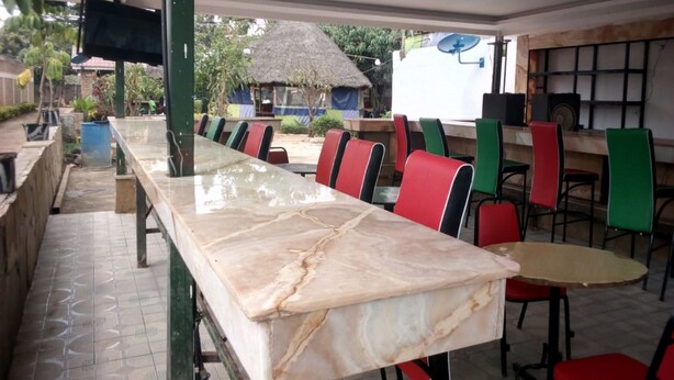 A restaurant with a long marble counter and multiple chairs. - Serengeti Gardens Hotel (Nairobi)