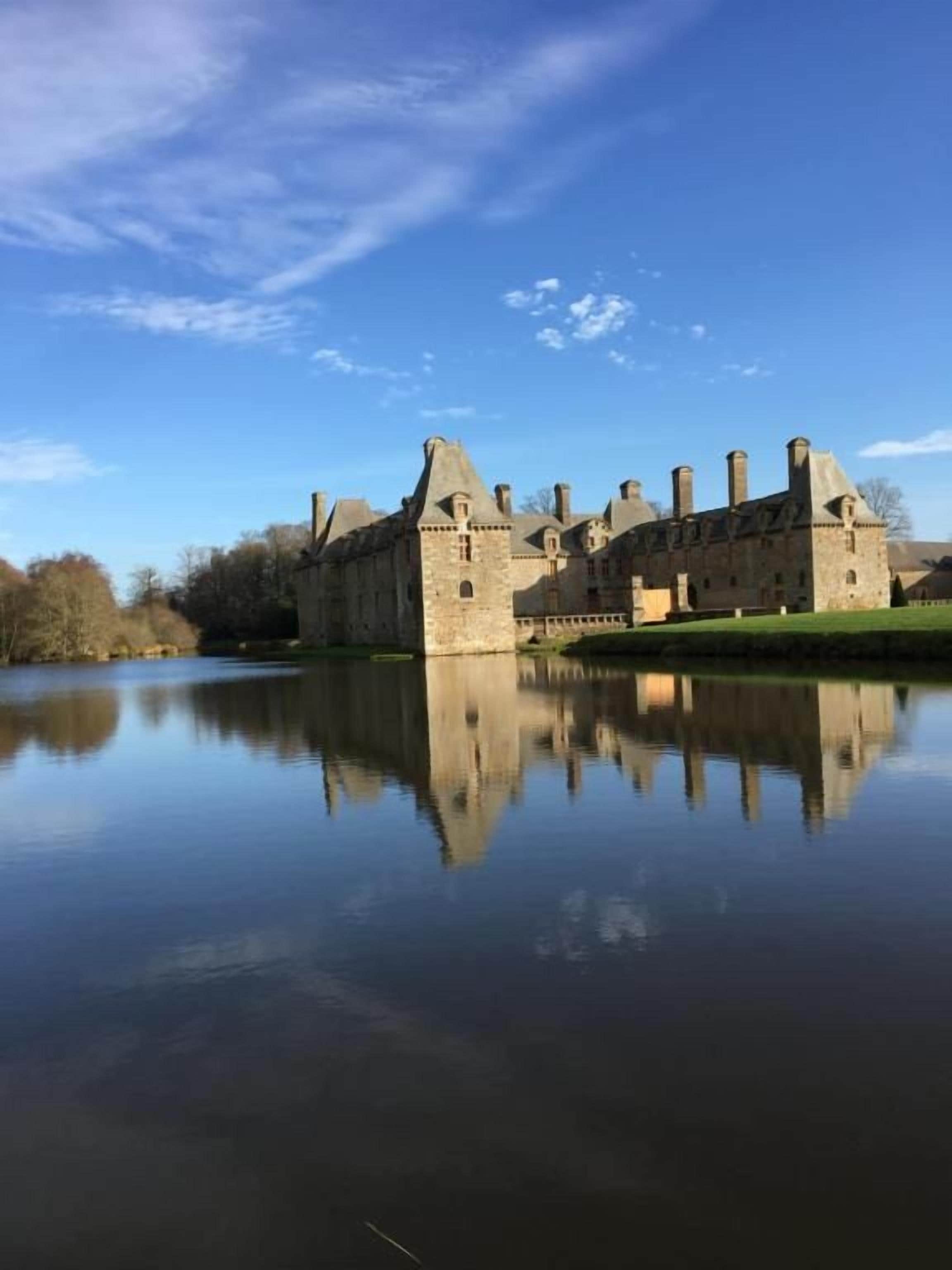 A historic castle with a moat, reflecting its architecture.