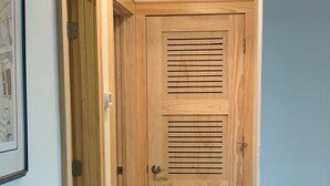 Una porta de fusta amb llistons horitzontals, un interruptor de llum i un detectiu de fum a la paret.