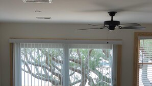 Habitació amb un llit, una taula de vidre i un balcó amb barana de fusta.