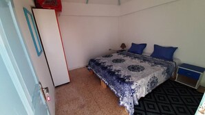 Un dormitorio pequeño y ordenado con cama, mesita de noche, escritorio y armario.
