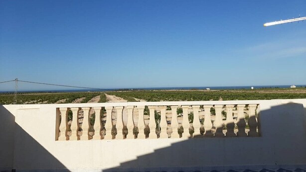 Un balcón con vistas a un paisaje costero, incluyendo cielo despejado y horizonte lejano.