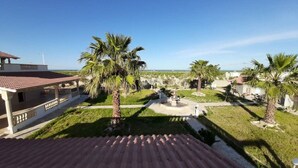 Un patio con palmeras, una fuente y un edificio con techo de tejas rojas.