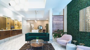 A modern hotel lobby with a green sofa, a round coffee table, and a reception desk. - The Vault Hotel (Houghton)