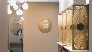 A modern bathroom with a mirror, round wall decoration, and a series of cabinets with a decorative screen. - The Vault Hotel (Houghton)