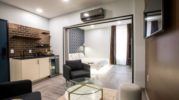 A compact living space with a kitchenette, a dining area, and a bedroom. - The Vault Hotel (Houghton)