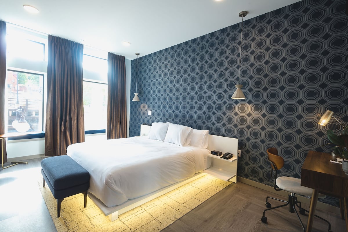 Ein modernes Hotelzimmer mit einem großen Bett, einem Schreibtisch und einem Sessel.