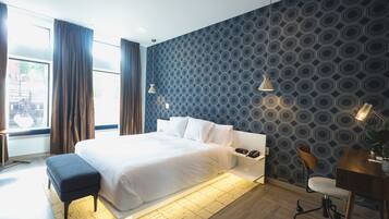 A modern hotel room with a large bed, a desk, and a chair.