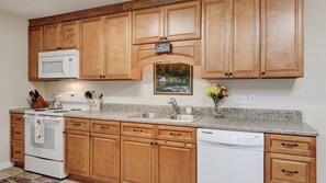 A kitchen with wooden cabinets, a microwave, a stove, a dishwasher, and a sink.