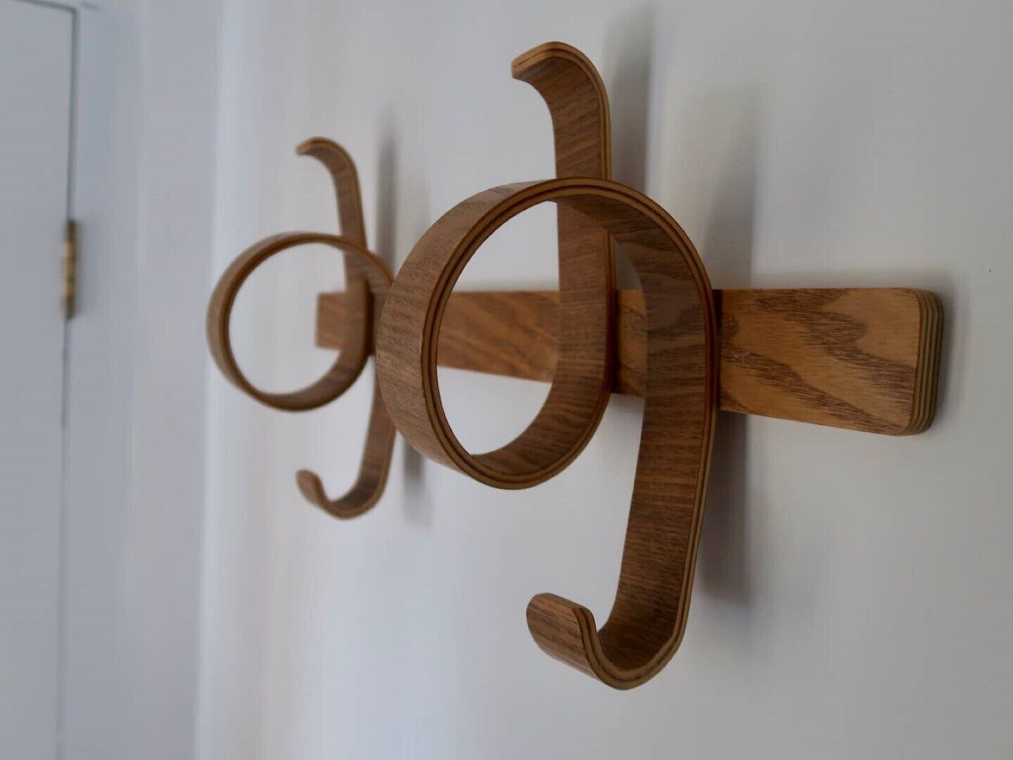 A wooden wall-mounted coat rack with a simple, functional design.
