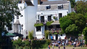 Ein Pub am Flussufer mit Außenbereich und einem Schild mit der Aufschrift 'The White Swan'.