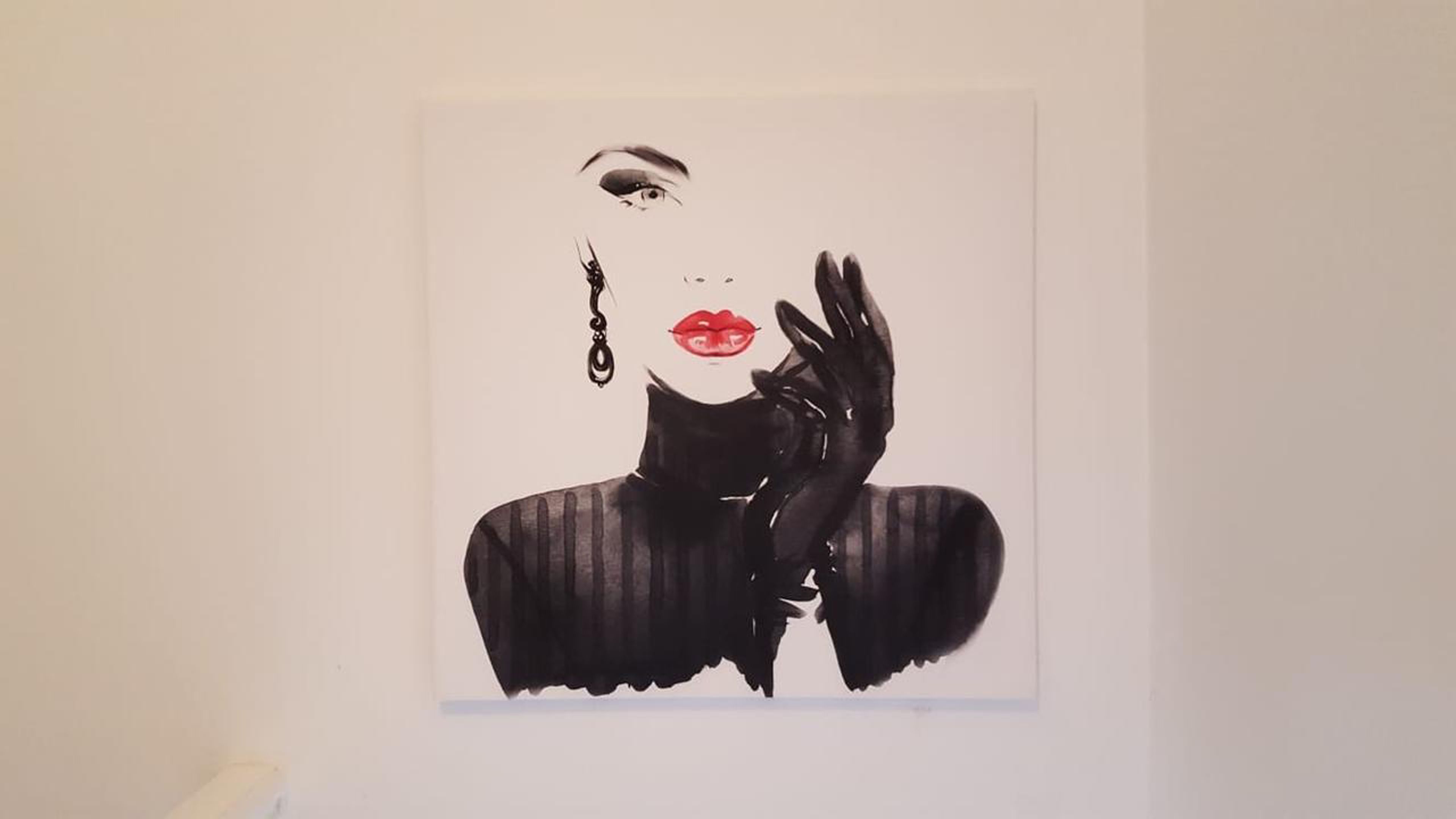 A painting of a person with a hand gesture, displayed on a wall.