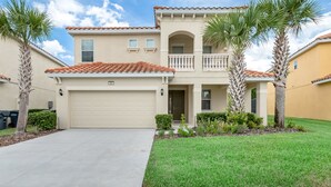 A two-story house with a beige facade, a red-tiled roof, and a front garage. - Impressive Waterfront Retreat Near Disney With Cinema Room - 5bd/4ba PH - Rav5341 (Davenport)
