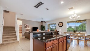 A spacious kitchen with a central island, a dining area with a chandelier, and a staircase leading to another level. - Impressive Waterfront Retreat Near Disney With Cinema Room - 5bd/4ba PH - Rav5341 (Davenport)