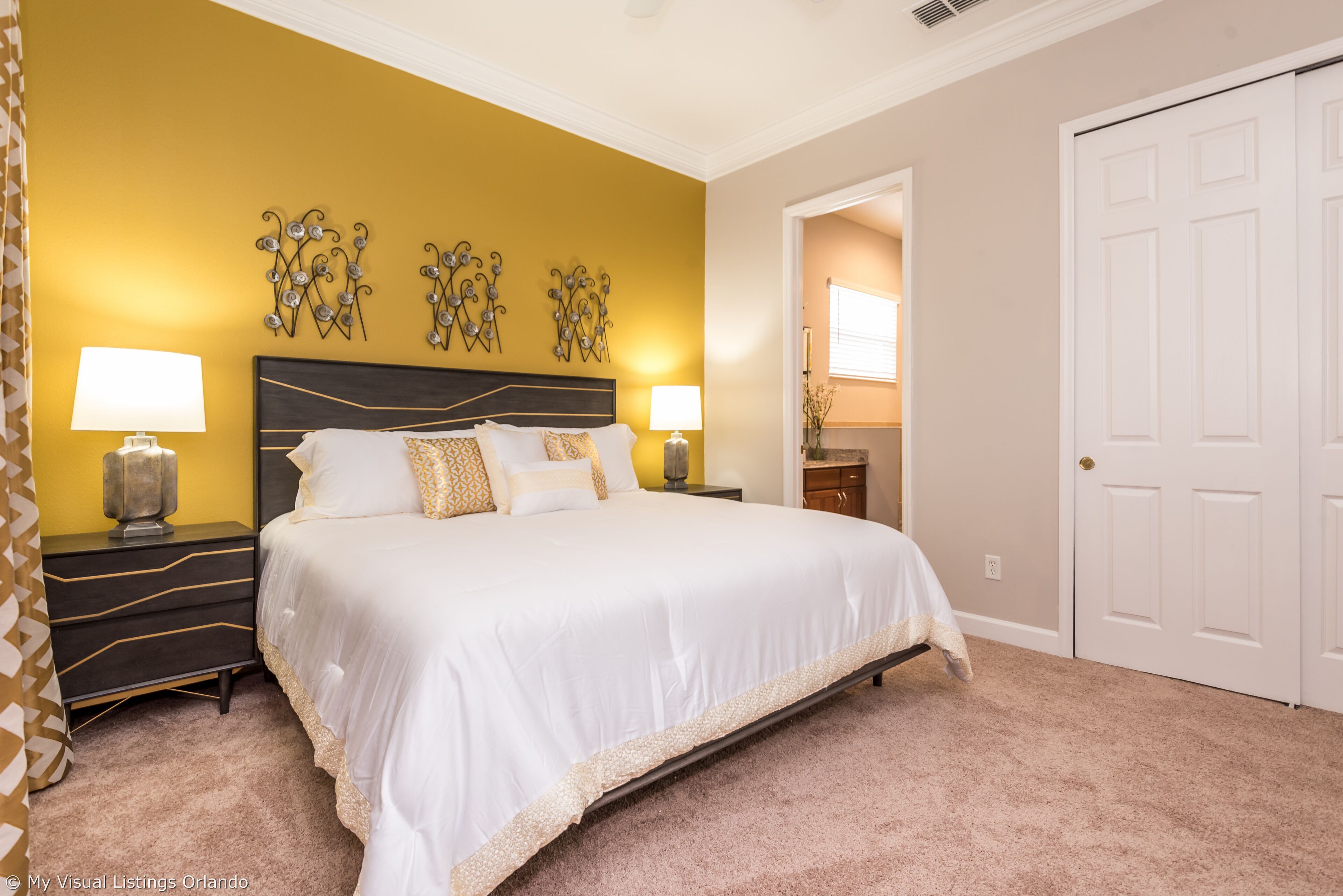 A bedroom with a large bed, two bedside tables, and decorative wall art.