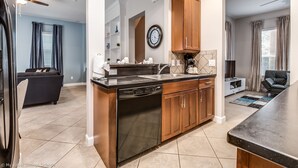 A modern kitchen with a dishwasher, wooden cabinets, and a large clock on the wall. - Stylish NEW Renovation in Reunion Resort - Large Patio and Pool Deck 3bd/3.5ba #3ru456 (Kissimmee)