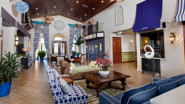 Eine großzügige Lobby mit hoher Decke, Wandverkleidung mit Muster und verschiedenen Sitzbereichen, darunter Sofas und Sessel.