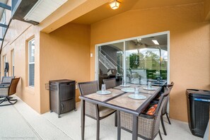 An outdoor patio with a table set for dining, wicker chairs, a trash bin, and a glass door leading to a staircase. - Private Pool Home With Fantastic Upgrades. Very Safe for Children! - 5av534 (Davenport)