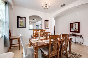 A dining area with a wooden table set for four, surrounded by upholstered chairs. - Enjoy Stunning Sunset Over Lake View! Near Disney #6av131 (Davenport)
