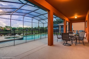 A covered outdoor area with a pool, chairs, and a table. - Enjoy Stunning Sunset Over Lake View! Near Disney #6av131 (Davenport)