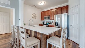 A kitchen with a central island, wooden cabinets, stainless steel appliances, and a clock on the wall. - Stylish and Contemporary Vista Cay Hideaway - Lake View 3bd/2ba #3vc4126 (Orlando)